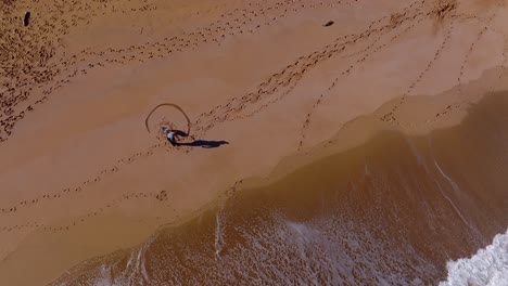 Vista-Aérea-De-La-Persona-Que-Dibuja-El-Corazón-Del-Amor-En-La-Arena-A-Lo-Largo-De-Una-Playa-En-España