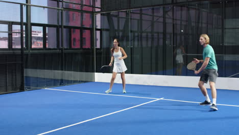 women playing padel tennis on indoor court, enjoying competitive match