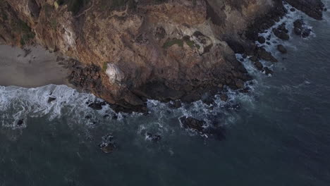 Vista-Inclinada-Hacia-Abajo-De-La-Costa-Del-Acantilado-En-California-Con-Olas-Oceánicas-Rompiendo-En-Las-Rocas,-Vista-Superior-De-Pájaros-Aéreos