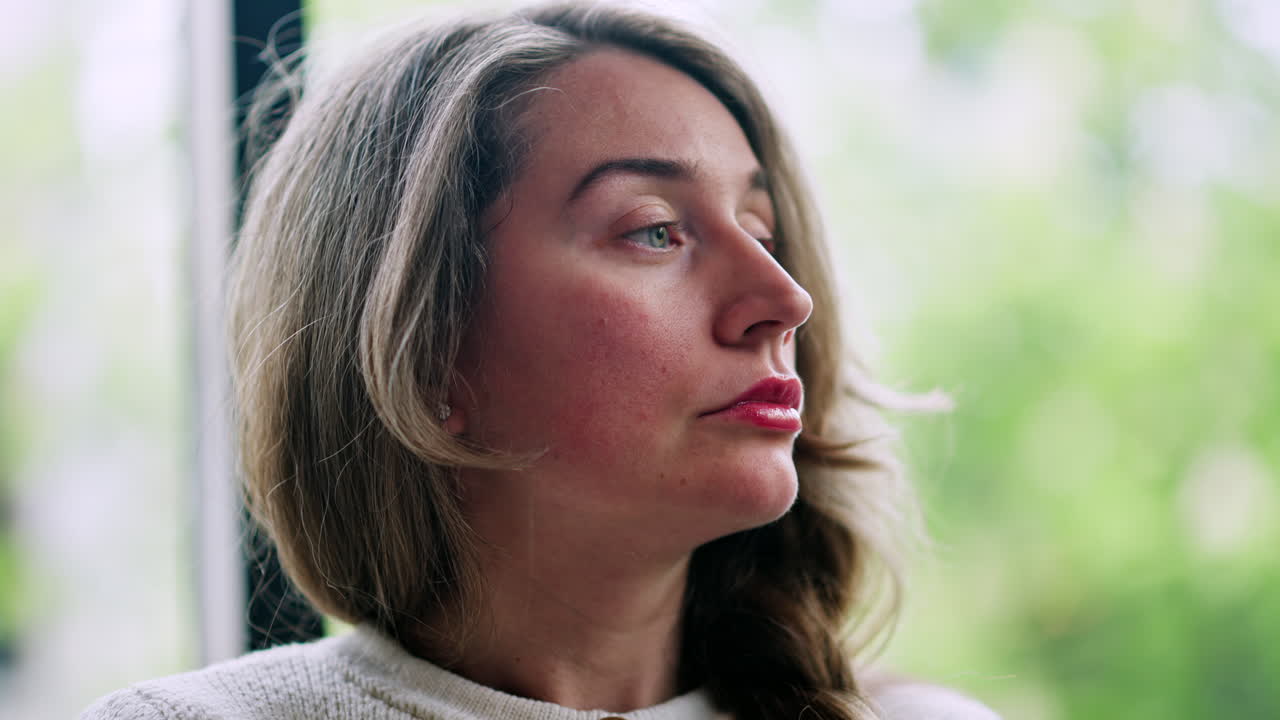 Brunette, sad woman looking around, near a window