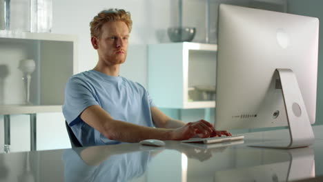 serious freelancer writing article at home. focused ginger manager closeup.