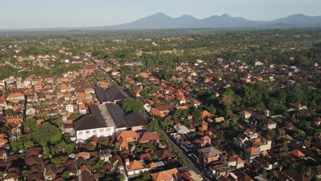 Toma-De-Establecimiento-Del-Centro-De-Ubud-Con-Casas-Tradicionales-Balinesas-Y-Volcanes-Al-Fondo,-Bali,-Indonesia.