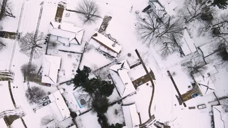 descending over neighborhood of snowcapped roofs