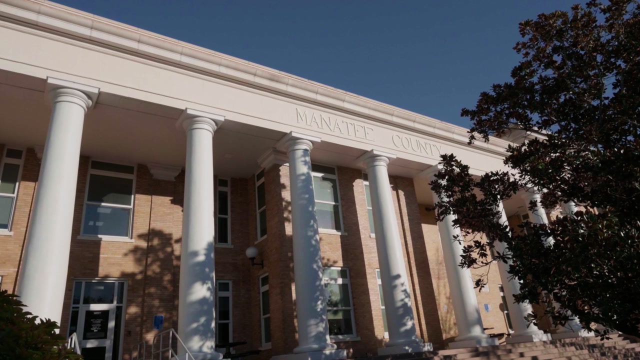 old Southern Manatee County courthouse in Bradenton, Florida at sunset, white columns and Manatee County label on the top facade