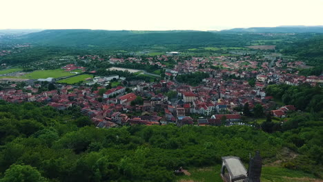 Volando-Más-Allá-De-Un-Monumento-Hacia-La-Ciudad-De-Volvic,-Francia-Frente-A-él