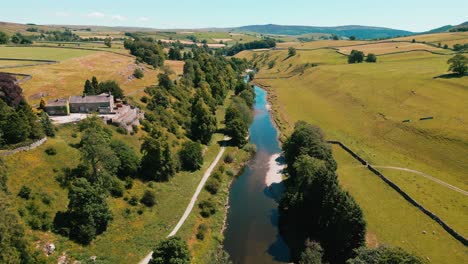 ariel drone footage of peaceful river surrounded by farmland in the yorkshire dales national park, uk