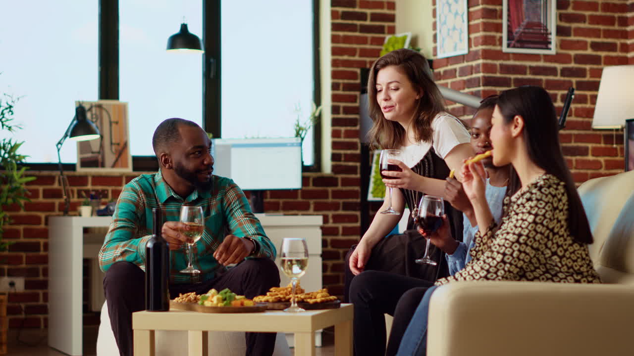 Mates having lively conversation, throwing party in modern apartment living room
