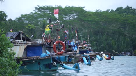 fishermen's boats lean on the white sand beach and the blue sky of pangandaran, west java, indonesia, with beautiful red and white flags fluttering