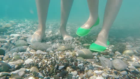 Beine-In-Schutzschuhen-Auf-Dem-Kiesboden-Des-Meeres-Sicheres-Baden-Im-Meer-Konzept