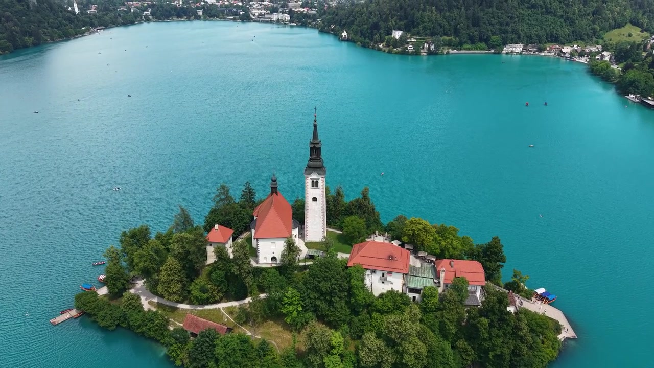 Ripresa con drone del Lago di Bled e della Chiesa Cattolica della Vergine Maria su una piccola isola circondata da acque alpine turchesi.