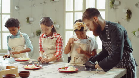 chef y niños cortando champiñones en la clase maestra culinaria