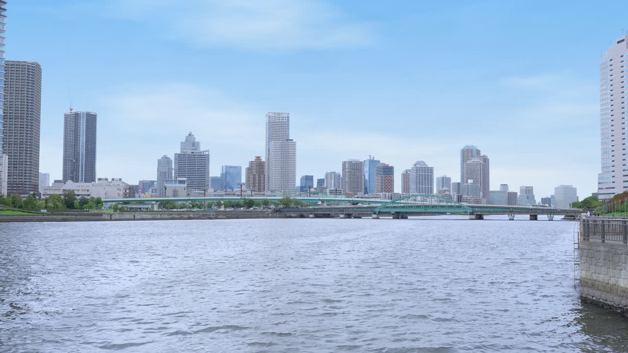 A wide, peaceful shot of the expansive Tokyo Bay with the distant cityscape and a bright sky