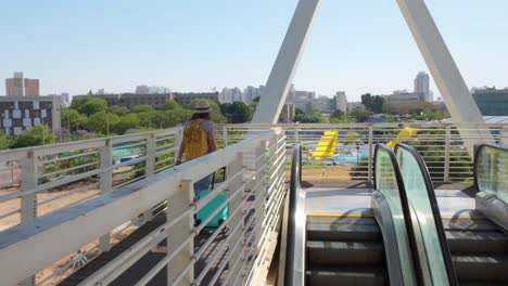 woman walking on a bridge with escalators and city view