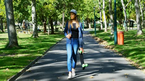 Frau-Mit-Skateboard-Läuft-Auf-Der-Straße-In-Der-Nähe-Des-Parks-4k