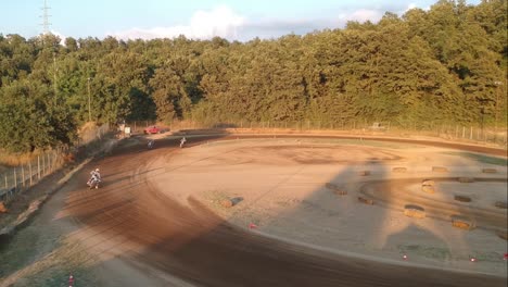 motocross que deriva en una curva de un circuito de pista de tierra, vista alta