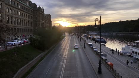 Light-traffic-drives-past-the-Czech-Ministry-of-Industry-and-Trade-in-Prague-as-pedestrians-stroll-along-the-bank-of-the-Vltava-River-at-sunset