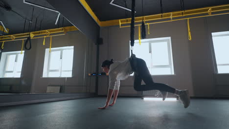 entrenamiento de suspensión eficaz moderno en el gimnasio joven mujer atlética está haciendo ejercicios para las piernas