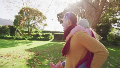 Video-of-happy-caucasian-father-piggybacking-daughter-in-sunny-autumn-garden