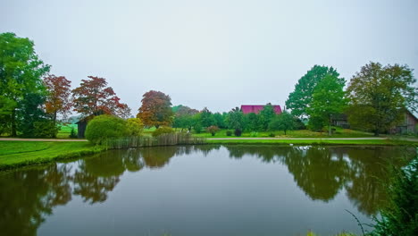 lake in bucolic and idyllic verdant landscape with red roof in background