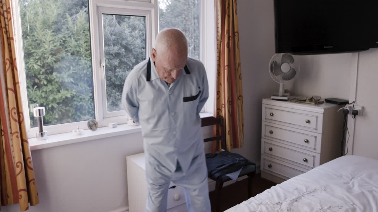 An elderly man in pajamas in a bedroom