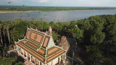 hermosa pagoda con pájaros en cámara lenta volando, al lado del pintoresco río mekong