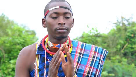 maasai male fixing his traditional attire and greets to a camera