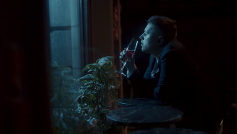 a man drinking alone in a bar at night