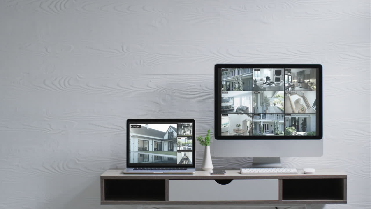 Monitor montato a parete e portatile su scrivania con visualizzazioni di telecamere di sicurezza sugli schermi, in slow motion.
