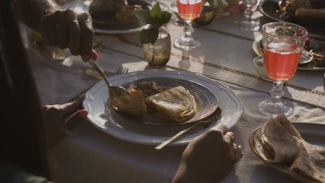 people's hands serving and sharing food at a dining table during a meal