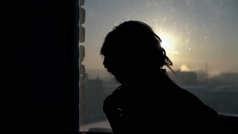 mujer de movimiento pasado mirando fuera de la ventana grande al atardecer