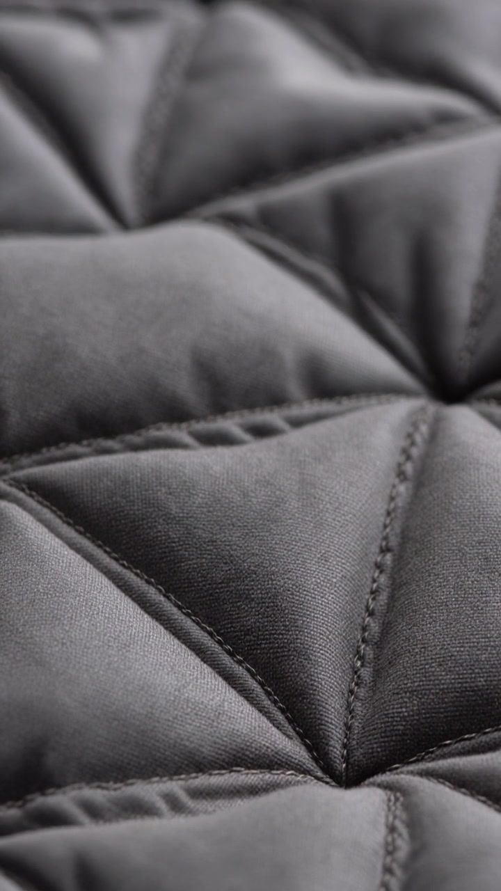 Primo piano di una coperta ponderata grigio scuro con cuciture trapuntate a triangoli geometrici