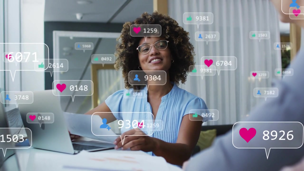 Woman reviewing docs glancing at laptop, heart and like bubbles appearing rising marketing metrics