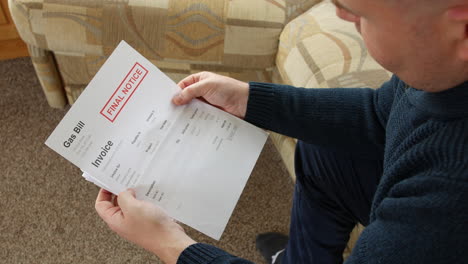 a man is opening a debt letter at home