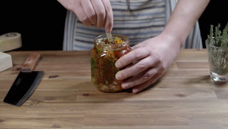 stir all the chimichurri ingredients in a glass jar, chef prepares argentine sauce for sados