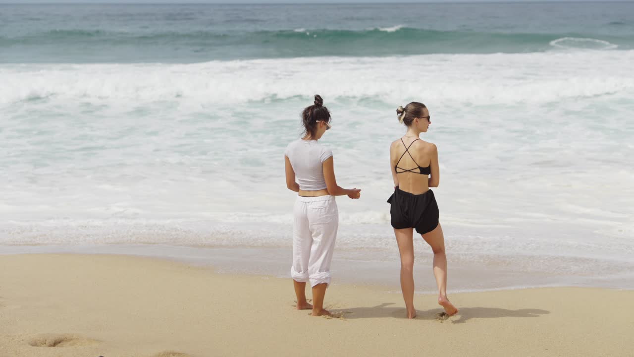 Two women on a sandy beach enjoying the ocean view
