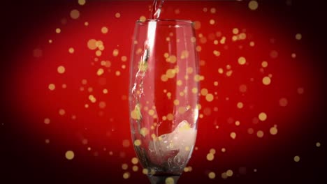 yellow spots floating over drink pouring into champagne glass against red background