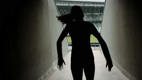 HANDHELD-TRACKING-Caucasian-female-athlete-entering-stadium-before-morning-training.-Shot-with-anamorphic-lens