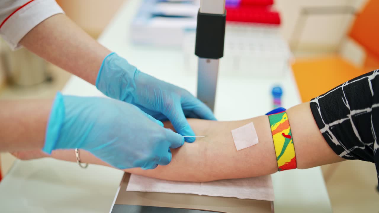 Medical assistant taking a blood sample from vein. Hands of doctor inject a syringe into a vein to a female patient. Close-up.