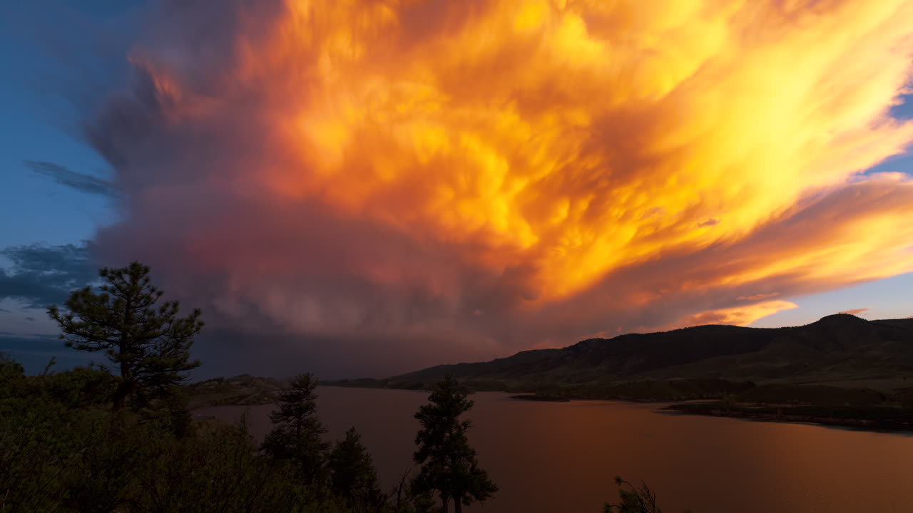Ein Sturm schlängelt sich durch die Berge Colorados, während die untergehende Sonne Orangen- und Rottöne in den Himmel wirft