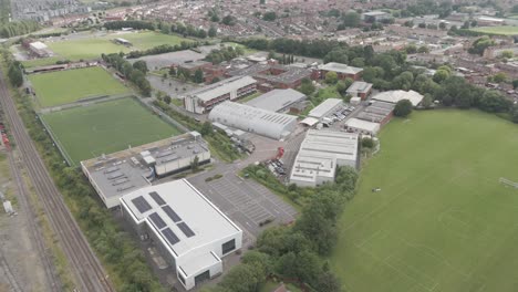 aerial view of a large campus or sports complex with multiple buildings, sports fields, and adjacent residential areas.