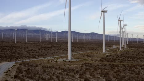 Wind-turbine-farm-rising-aerial-view-across-many-turbines-on-vast-mountain-landscape