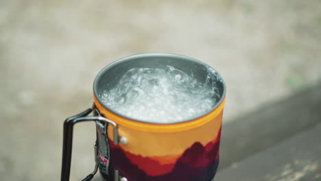 Agua-Hirviendo-En-Una-Taza-Turística-De-Esmalte-Rojo-Y-Amarillo