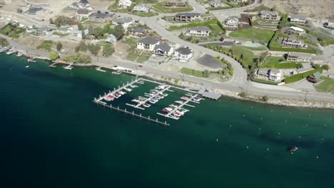 Drone-flying-over-houses-towards-lake-and-mountains