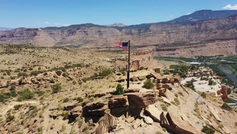 drone footage of flag on top of mountain waving in the the wind