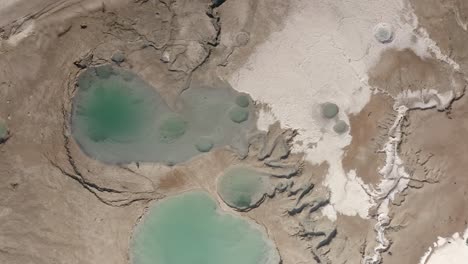 aerial view of a dried salt lake bed with pools of turquoise water