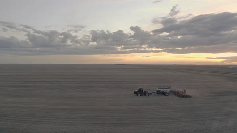 Traktoraussaat-Bei-Der-Arbeit-Auf-Dem-Feld-Während-Des-Sonnenuntergangs-In-Saskatchewan,-Kanada