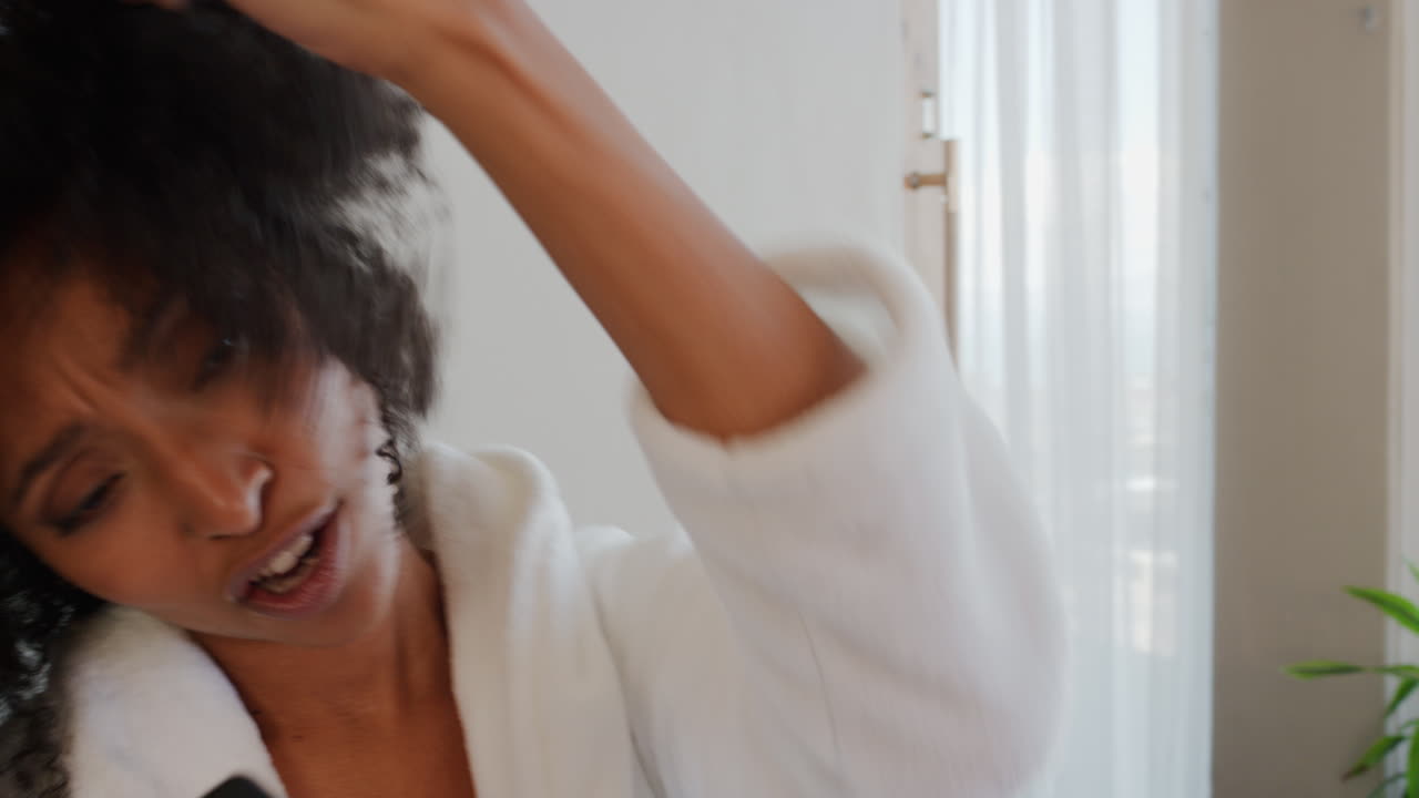 felice donna afroamericana che canta a casa divertendosi celebrando lo stile di vita di successo ballando godendosi l'intrattenimento musicale karaoke