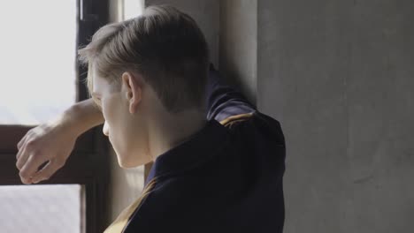 Young-male-standing-near-windows