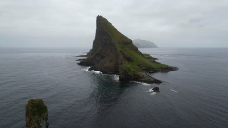 Toma-Aérea-Hacia-Atrás-Desde-Tindholmur-Que-Revela-Drangarnir-En-El-Océano-Atlántico-Con-Gaviotas-Volando-Alrededor