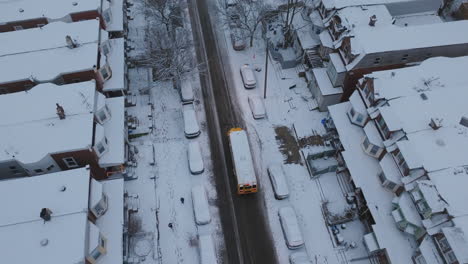 Aerial drone footage following a school bus as it drives on its route in snow covered neighborhoods in West Philadelphia, Pennsylvania.